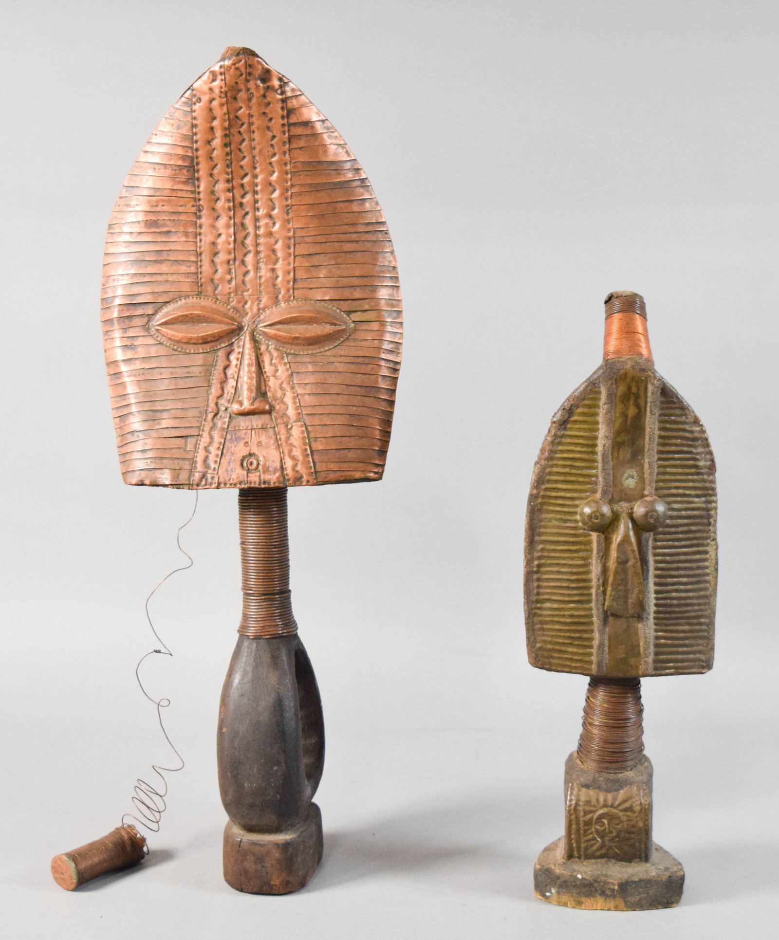 Pair of African Kota Style Reliquary Guardian Figures: Pair of African tribal Kota style reliquary guardian figures. Carved wood core wrapped in hammered copper and brass. Taller figure with partially detached finial. Taller figure 27 1/2" H x 10 1/2" W.