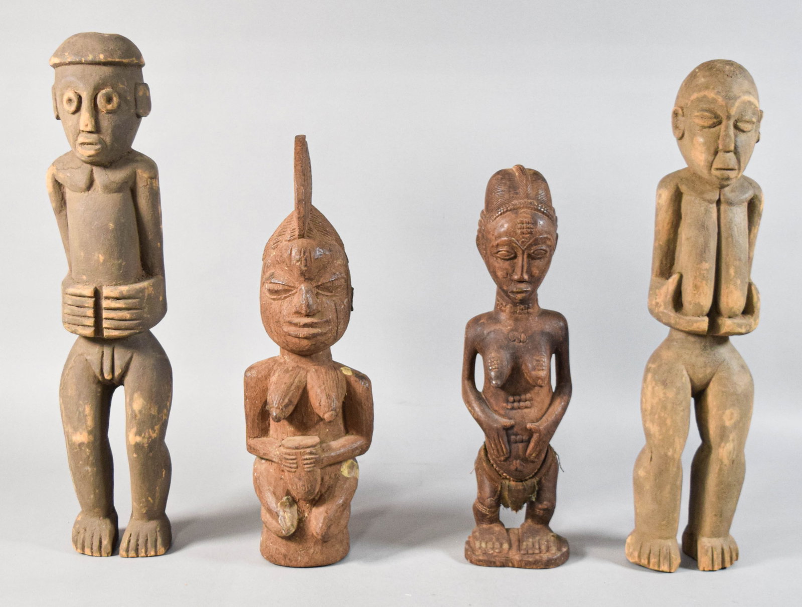 4 West African Style Carved Wood Figures: Group of four West African style carved wood figures. Includes two tall standing figures, a kneeling female figure, and a smaller standing female figure. Largest figure 22" H x 5" W x 4" D.