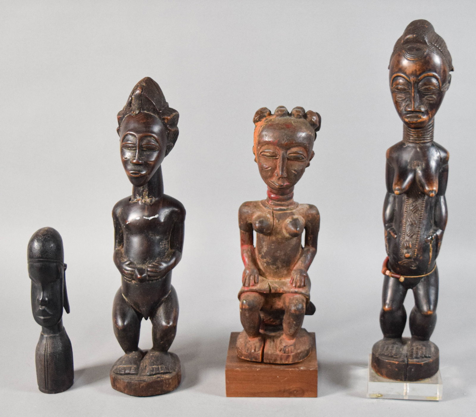 4 West African Style Carved Wood Figures: Group of four West African style carved wood figures, attributed to the Baule or similar cultures of Cote d'Ivoire. Two tall standing figures (one male and one female), one seated female figure on a b