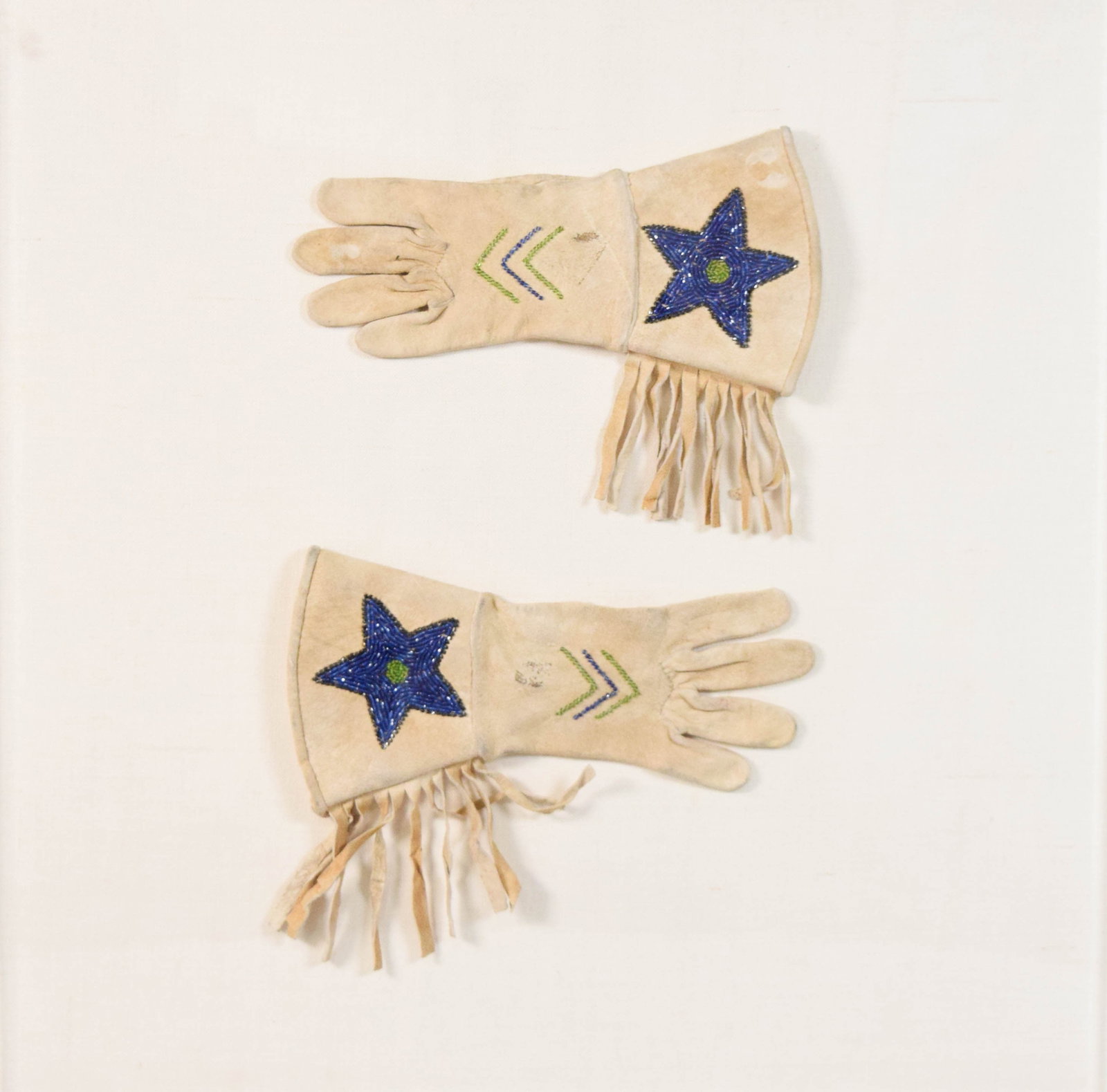 Pair of North American Indian Beaded Hide Gauntlets: Pair of small gauntlet-style gloves, likely of North American Plateau or Plains Indian origin, early 20th century. Mounted in acrylic shadowbox frame. 22 1/4" x 22 1/4" x 1 1/2" with frame.