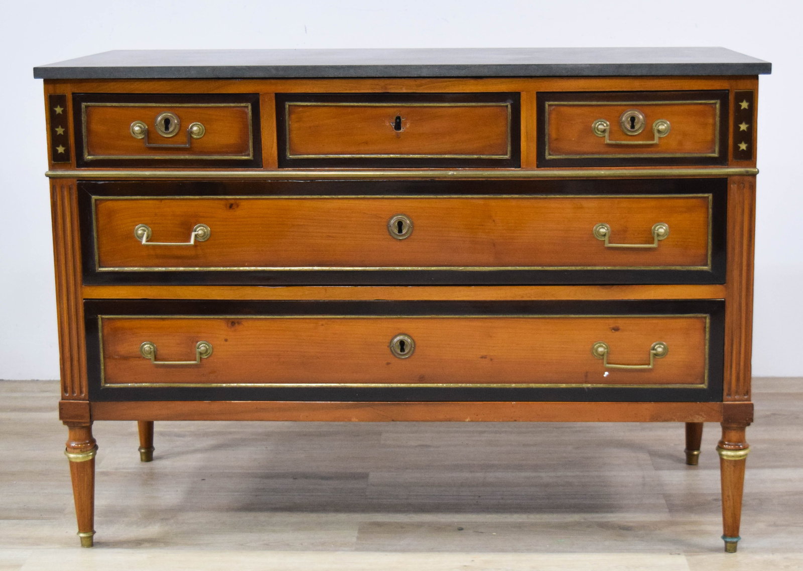 French Empire Commode with Stone Top: French Empire commode with a removable stone top and five drawers. Case constructed from fruitwood with ebonized borders and brass stringing. Corner blocks of the frieze decorated with inlaid brass st