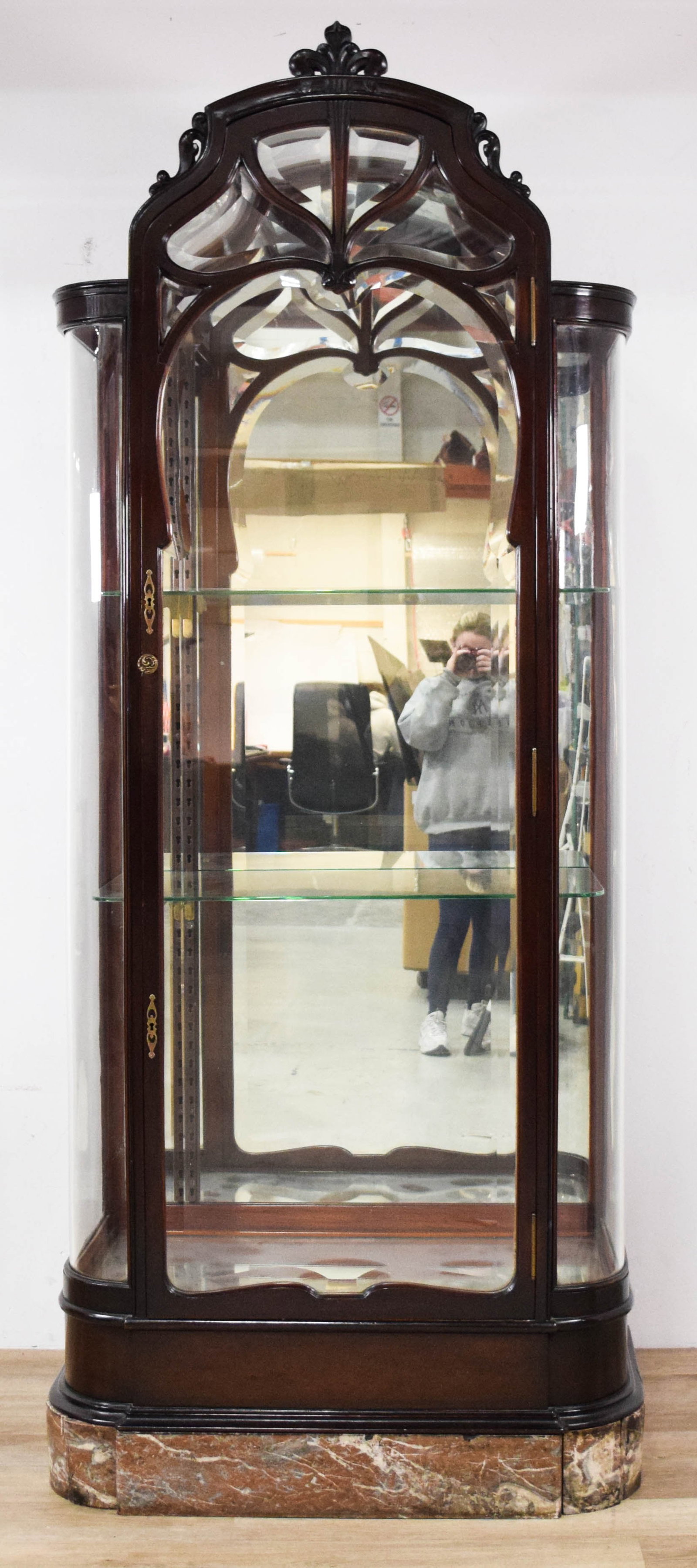 Art Nouveau Carved Mahogany Vitrine Cabinet: Art Nouveau mahogany vitrine cabinet. Carved wood cresting with fleur-de-lis and scroll motifs. Mirrored interior with three adjustable glass shelves on vertical tracks. Marble panels currently detach