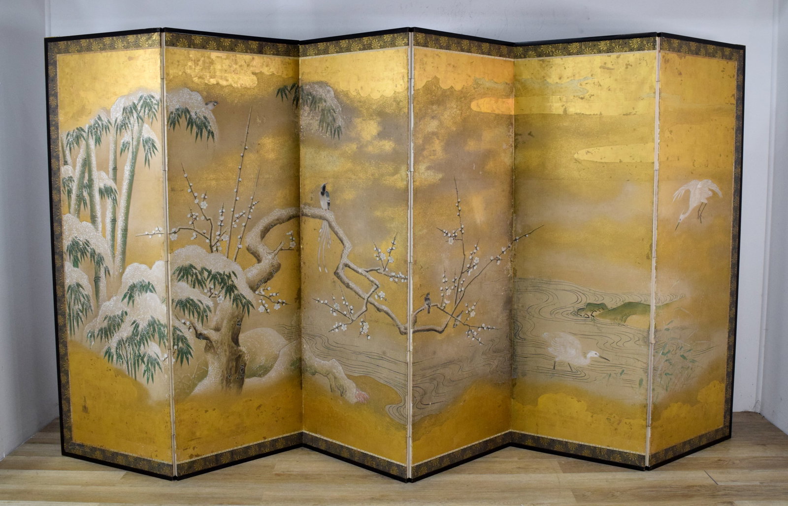 Japanese Kano School Folding Screen Late 18th Century: Japanese Kano School six-panel folding screen, late 18th century. Winter scene with plum tree, bamboo, and white egrets. Background composed of gold leaf with scalloped borders; painting bordered by s