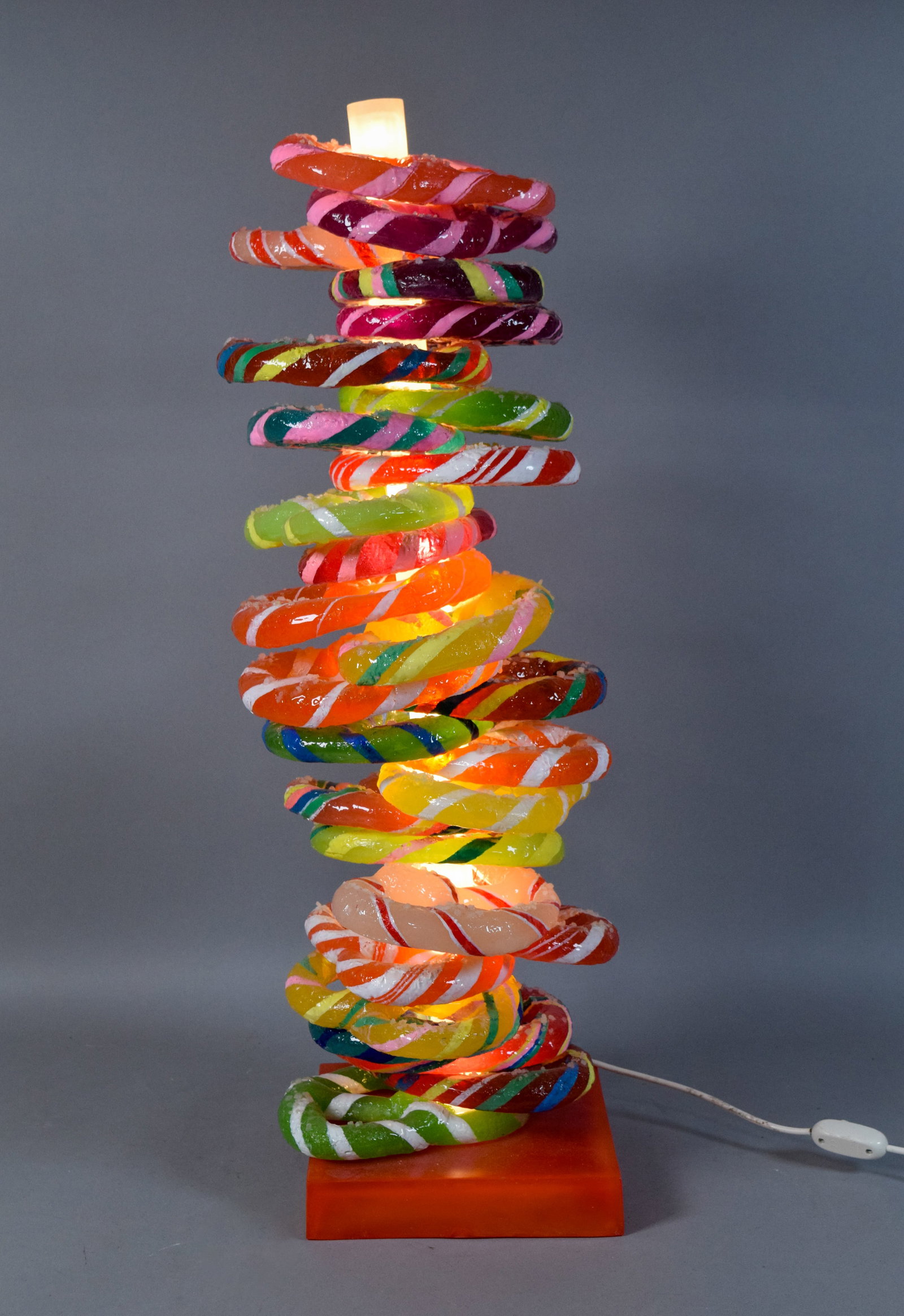 Pop Art Stacked Candy Pretzel Lamp: Contemporary pop art lamp featuring a central frosted white light column supporting a vertical stack of resin pretzels. Each pretzel topped with a crystalline granular texture intended to mimic salt o