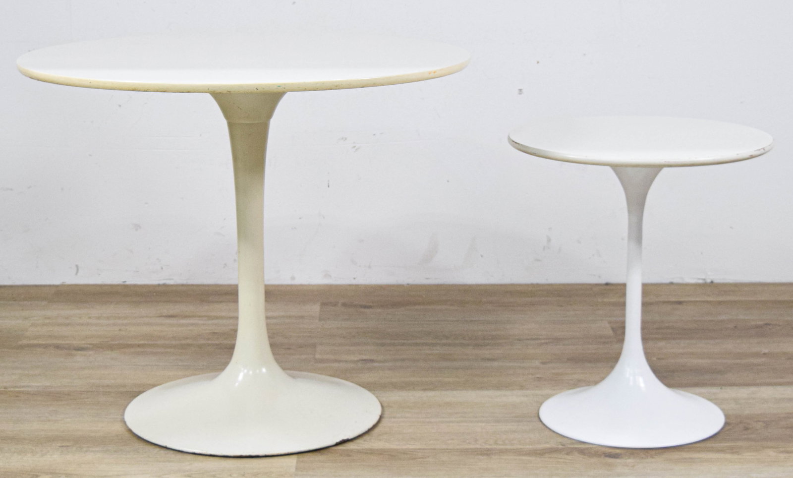 Two MCM White Tulip Pedestal Tables: Two Mid-Century Modern white Tulip pedestal tables. Includes one bistro-sized table and one smaller side table. Both appear unsigned. Larger table 25" H x 30" diameter.