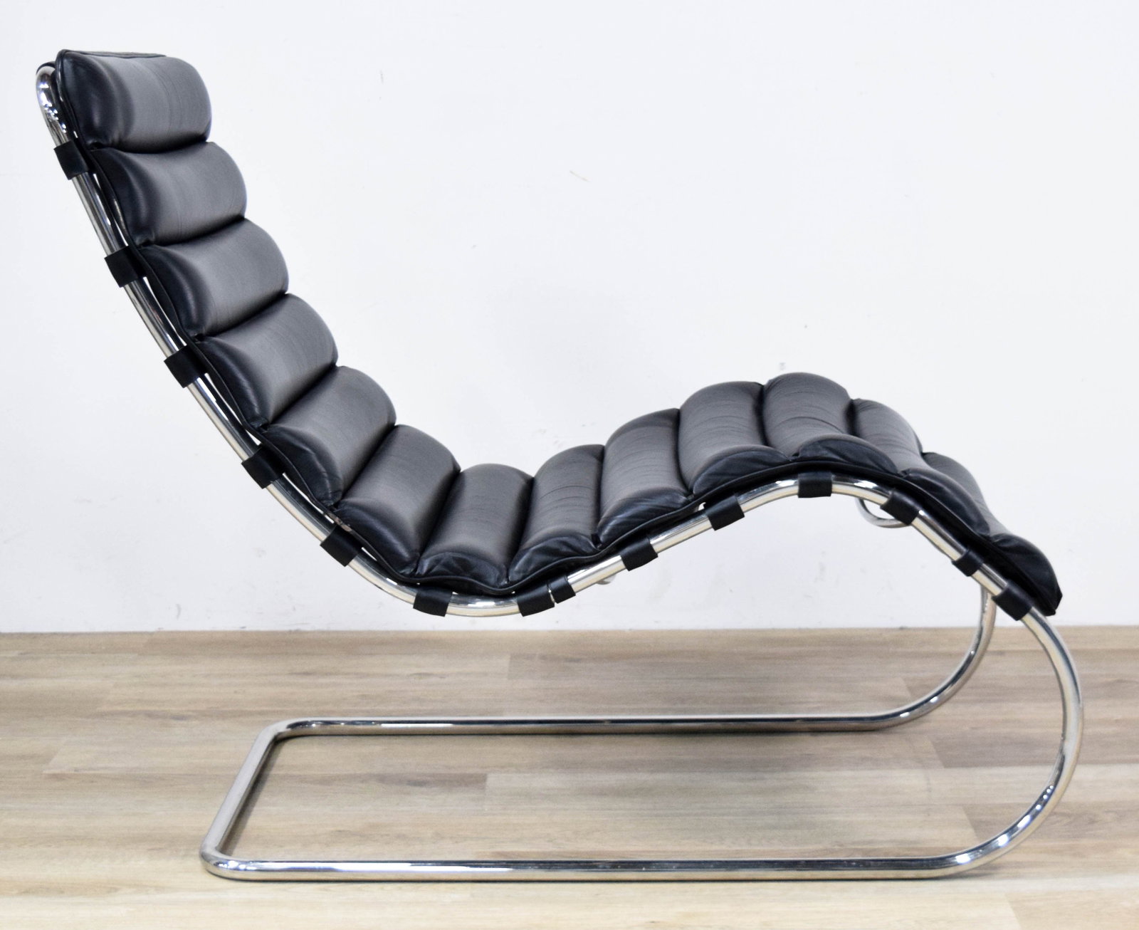 Mies Van Der Rohe Style Lounge Chair: Mid-Century Modern cantilevered lounge chair in the style of Ludwig Mies van der Rohe. Black leather upholstery on a chrome-plated steel frame. Appears unsigned. 37 1/2" H x 50" L x 24" W.