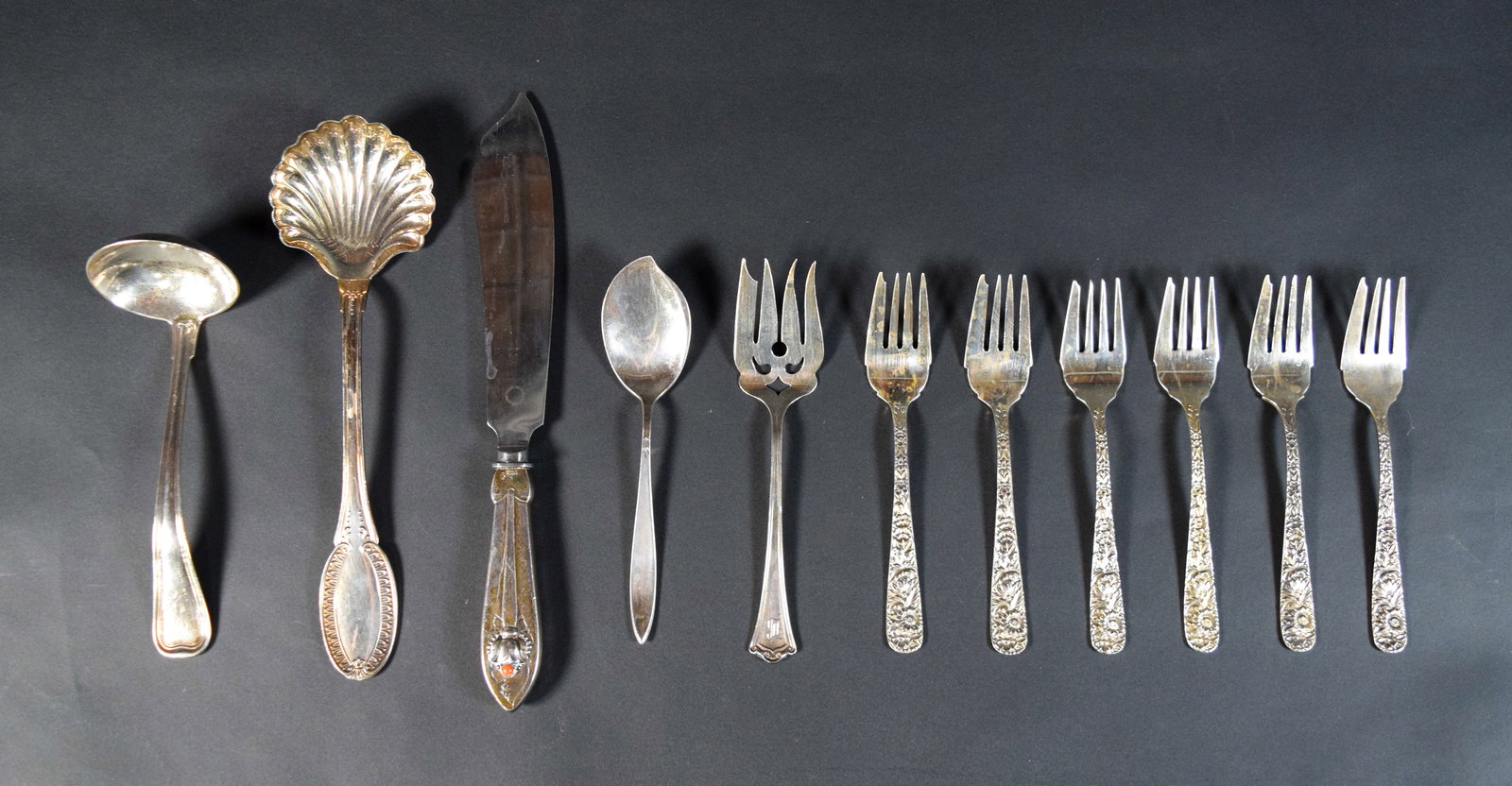11 Pieces of Sterling Silver Flatware Incl S. Kirk and Son, Gorham, and Georg Jensen: Eleven pieces of sterling silver flatware. Includes six S. Kirk and Son matching forks in a floral repousse pattern; a Gorham spoon with a leaf motif; a shell-form serving spoon with Italian hallmarks