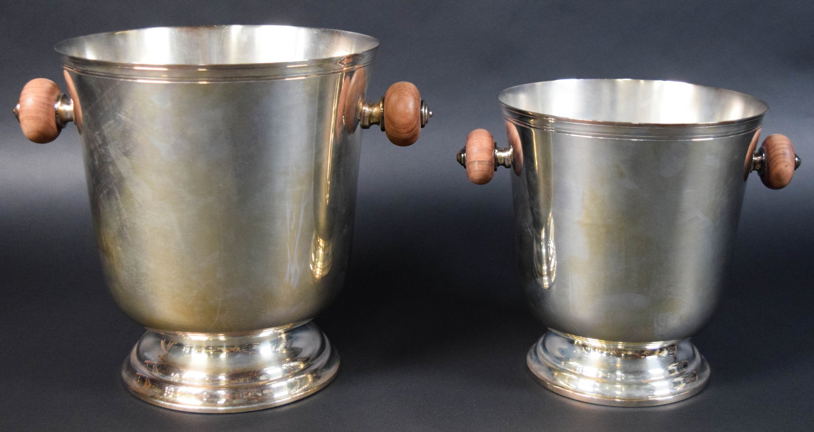 Pair of Christofle Silver-Plated Ice Buckets: Pair of Christofle silver-plated ice buckets or wine coolers with wood handles. Stamped Christofle on the base of each. Larger bucket 9 1/4" H x 8 1/2" diameter.