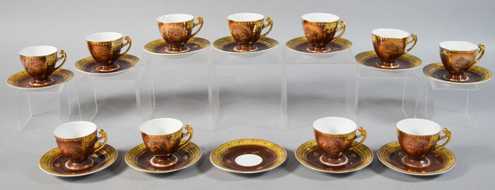 23 Piece Czechoslovakian Porcelain Tea Service: 23 pieces of a Czechoslovakian porcelain tea service, including eleven teacups and twelve saucers. Cups with transfer-printed courting scenes on burgundy ground with gilt detailing. Saucers with multi