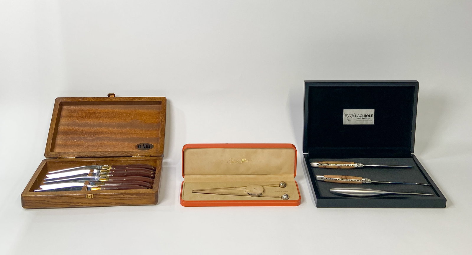 3 Boxed Laguiole, Saint-Hilaire, and Georg Jensen Cutlery and Barware Sets: Three boxed sets of specialty cutlery and bar service items by Laguiole, Saint-Hilaire, and Georg Jensen. One set of six Laguiole steak knives in an oak box. One pair of silver-plated articulated ice 