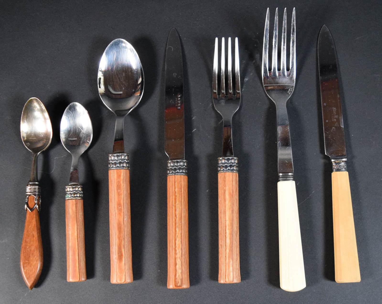 36 Pieces of French Flatware by Sabre and Si?¨cle Paris: 36 pieces of French stainless steel flatware by Sabre Paris and Si?¨cle Paris. The Sabre pieces feature dark wood-toned handles with decorative beaded metal ferrules. The Si?¨cle Paris pieces featur