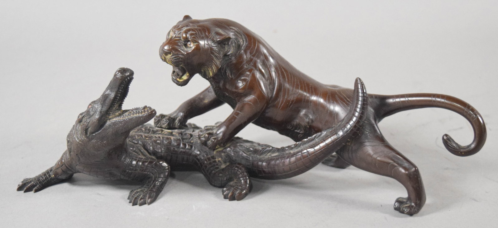 Japanese Meiji Style Bronze Sculpture of a Tiger and Crocodile: Japanese Meiji style bronze sculpture of a tiger and crocodile. The piece is cast with a dark brown patina, featuring intricate textures that highlight the tiger's fur and the crocodile's scales. The 