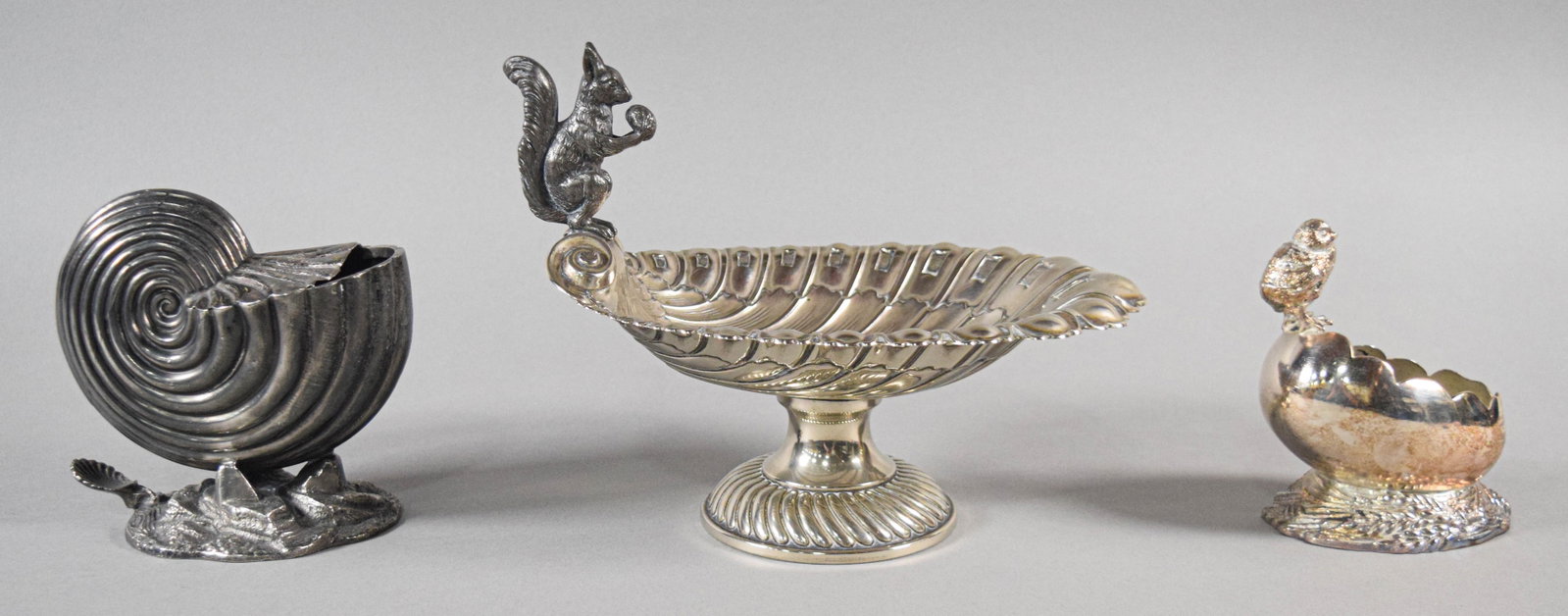 Three Victorian Style Silver Plated Decorative Tableware Items including Lee and Wigfull: A trio of silver plated decorative tableware items featuring naturalistic animal and maritime motifs. The lot includes a spoon warmer modeled as a nautilus shell supported by a cast rockwork base with