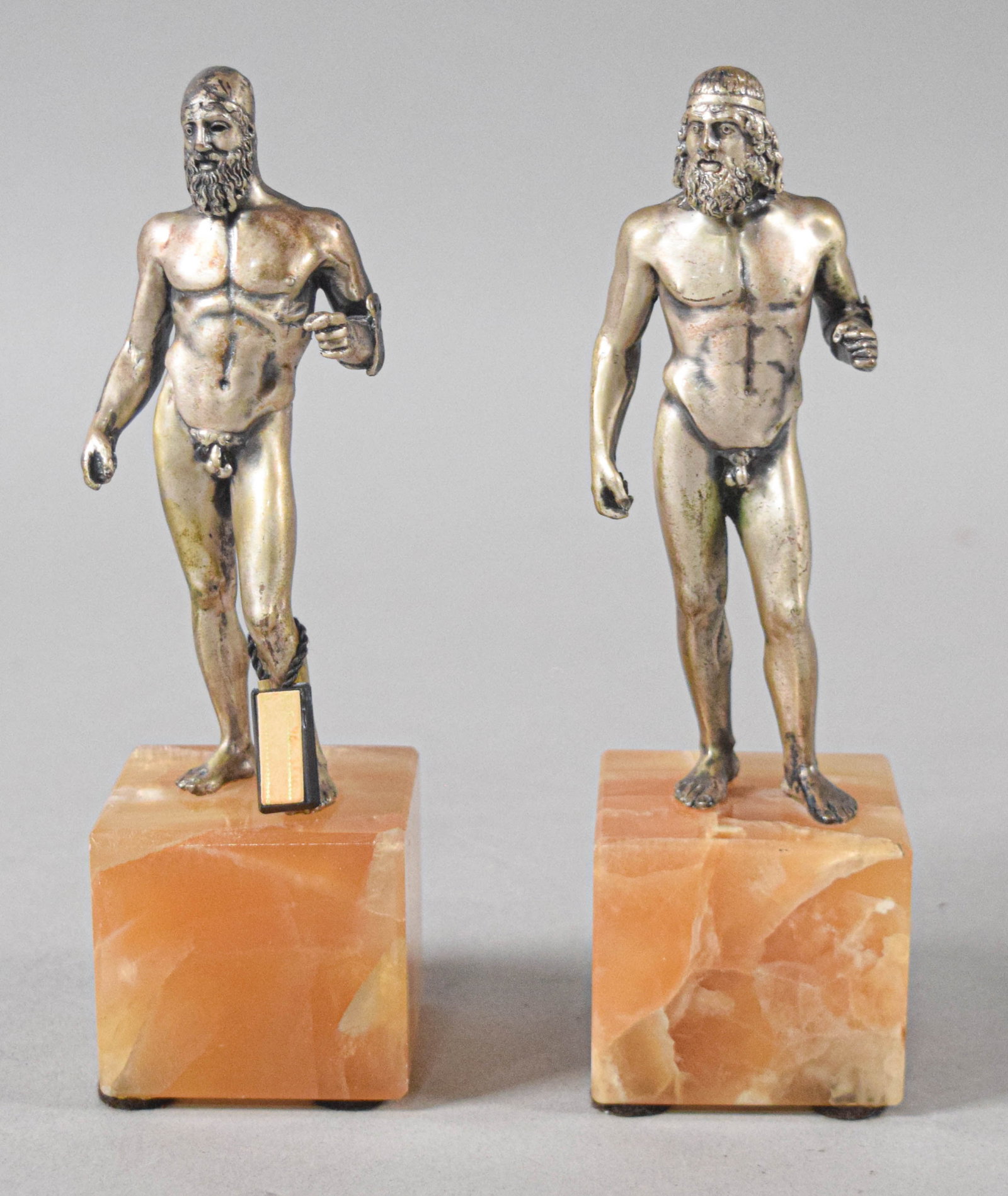 Pair of Italian Silvered Metal Riace Bronze Replicas on Quartz Bases: Pair of metal figurative sculptures on quartz bases, modeled after the ancient Greek Riace Bronzes. One figure retains a black and gold plastic label reading ETRURIA ARGENTO. 7" H x 2" W x 2" D. Locat