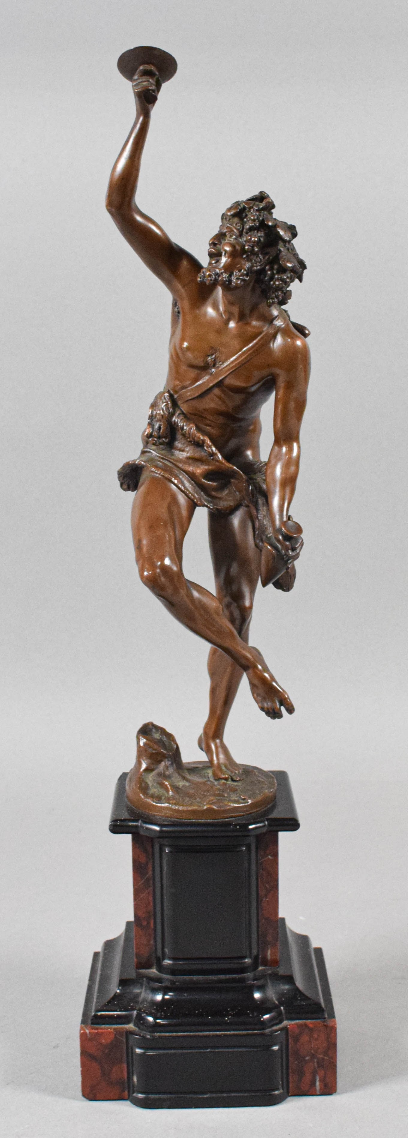 Max Lindenberg Bronze Sculpture of a Dancing Silenus: This bronze sculpture represents a dancing Silenus, a figure from Greek mythology associated with wine and revelry. The figure is depicted with a grapevine crown and an animal skin loincloth, captured