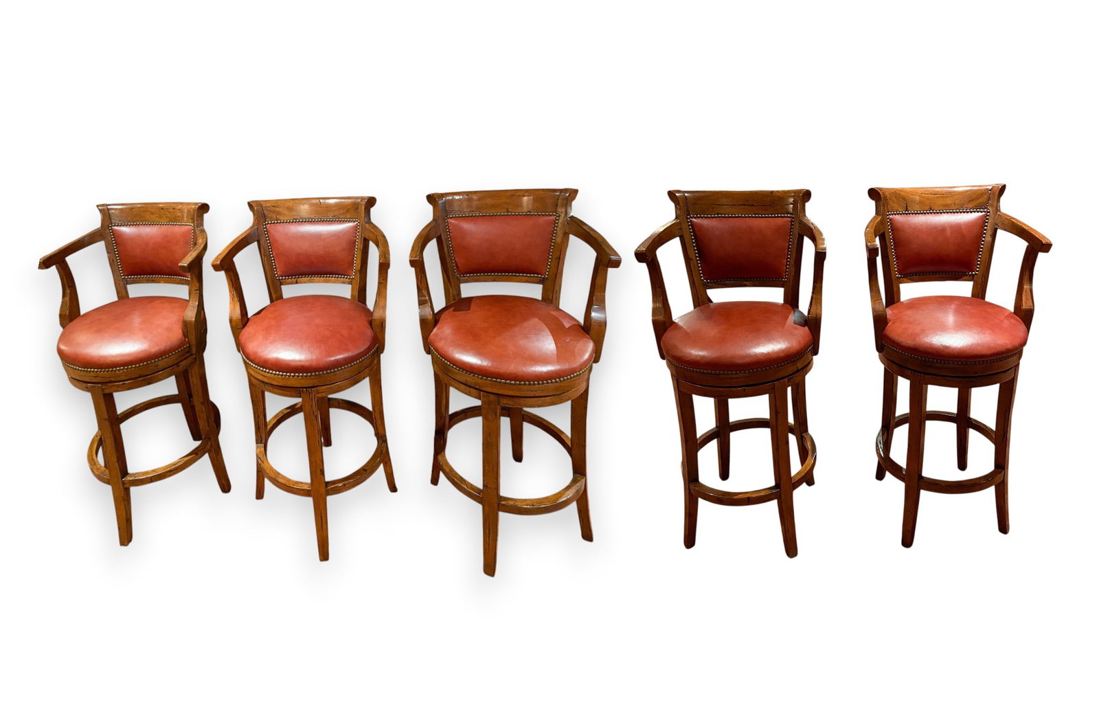 5 Guy Chaddock and Co. Country English Distressed Pearwood and Leather Swivel Barstools: A set of five professional grade swivel arm barstools manufactured by Guy Chaddock and Co. The stools are designed in a Country English style featuring a medium distressed finish on pearwood frames. E
