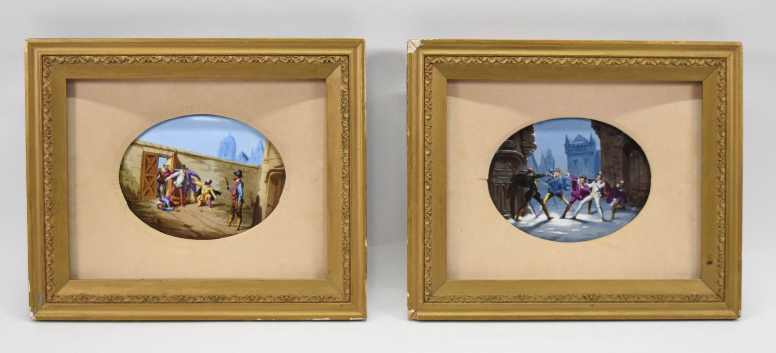 A Pair of Hand Painted Porcelain Plaques Signed E. Millet: A matching pair of oval porcelain plaques featuring hand painted historical genre scenes. Each plaque depicts figures in 17th-century attire including doublets, breeches, and ruffs. The first plaque s
