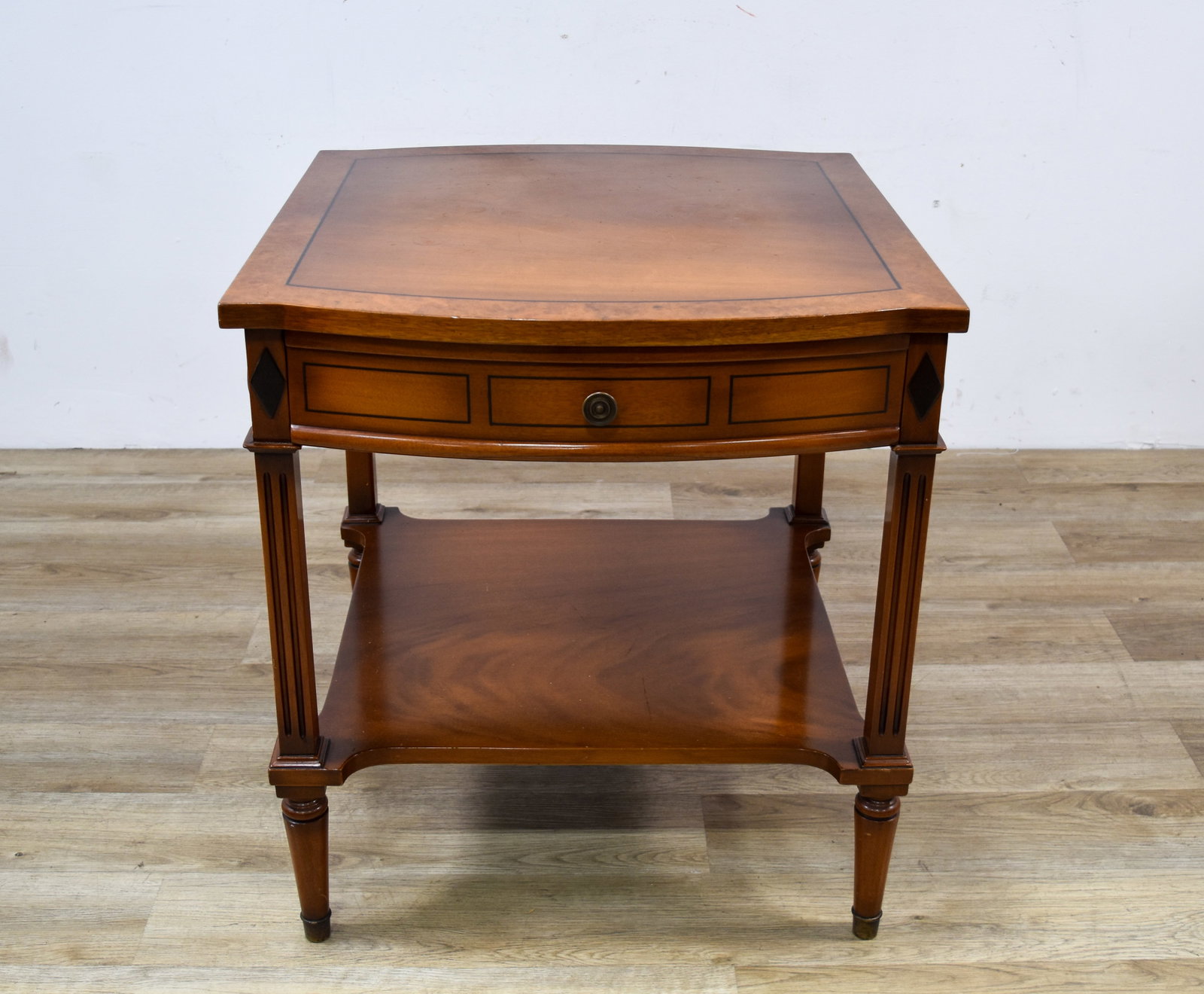 Neoclassical Style Mahogany and Burl Veneer Accent Table: This Neoclassical style accent table is constructed of mahogany-finished wood featuring burl wood and dark wood stringing veneers. The top is designed with a bowed front edge and a central veneered pa