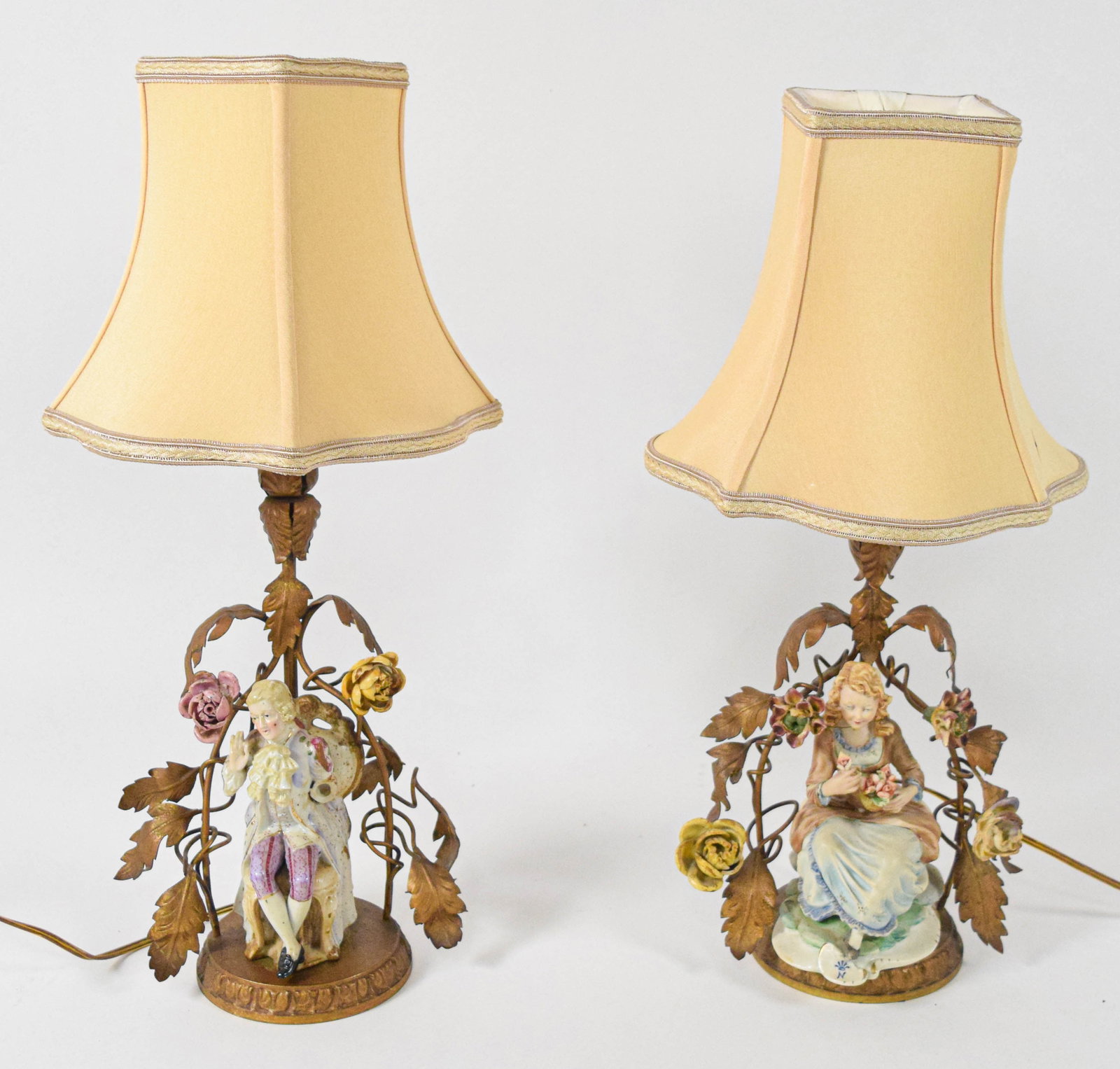 Pair of Capodimonte Porcelain and French Gilt Metal Figural Table Lamps: This pair of matching table lamps features hand-painted porcelain figures in the 18th-century style. One lamp depicts a seated man in a floral decorated waistcoat and lavender breeches, while the othe