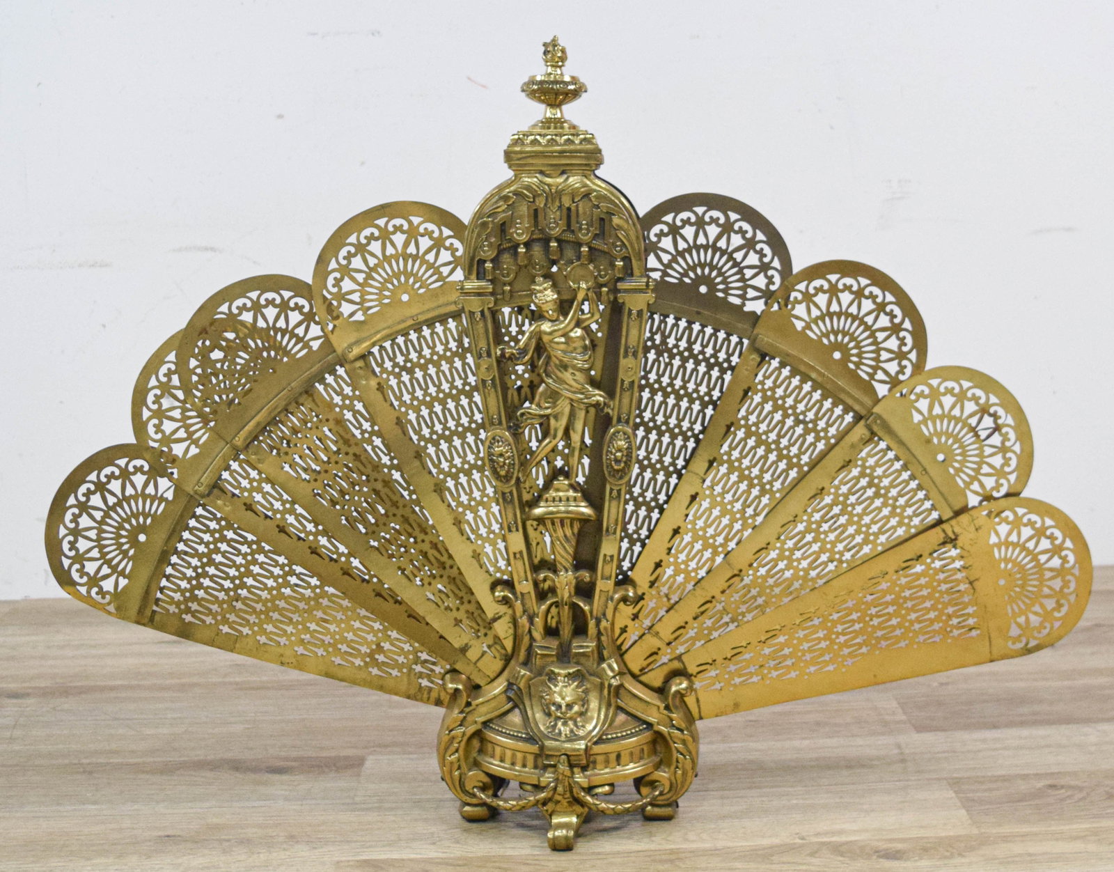 French Louis XV Style Gilt Brass Peacock Folding Fireplace Screen: A neoclassical revival fireplace screen constructed from cast and pierced gilt brass. The piece features a central decorative stand housing nine folding fan blades in a peacock-style arrangement. Each