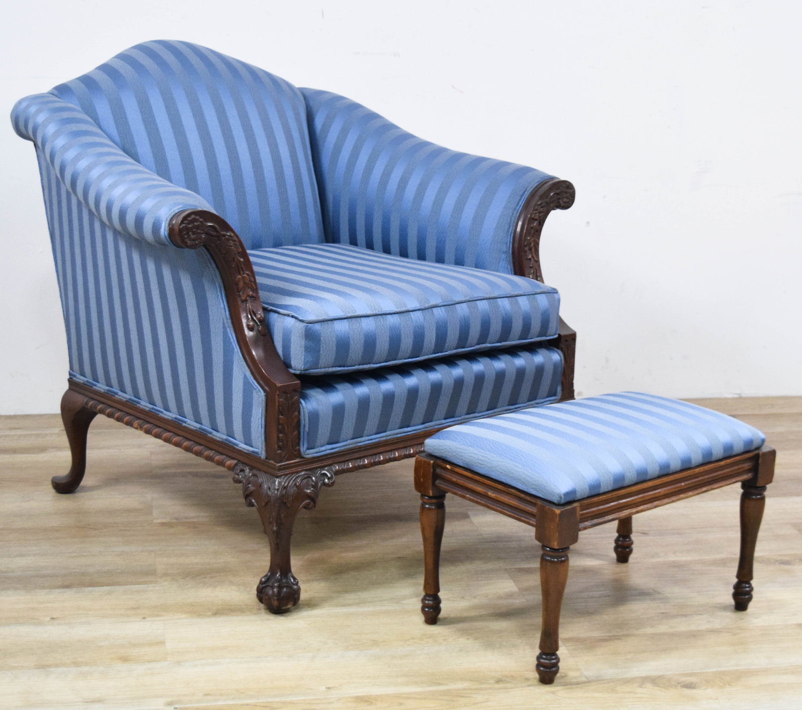 Chippendale Style Carved Armchair and Matching Footstool: This two-piece matching set features a Chippendale style armchair and a rectangular footstool, both upholstered in a blue and light-blue vertical striped satin damask. The armchair is designed with a 