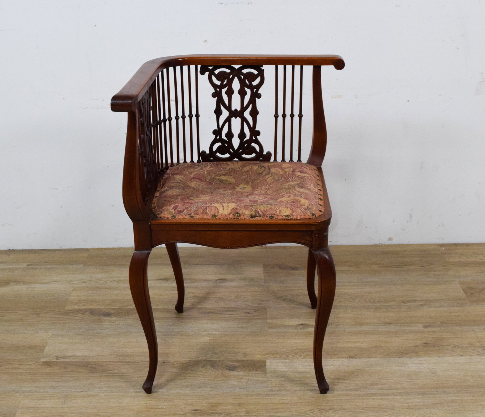 Late 19th Century Mahogany Corner Chair: Late 19th century mahogany corner chair. The piece features a horseshoe-shaped top rail supported by turned spindles and two central splats with foliate and scroll carvings. The padded seat is upholst