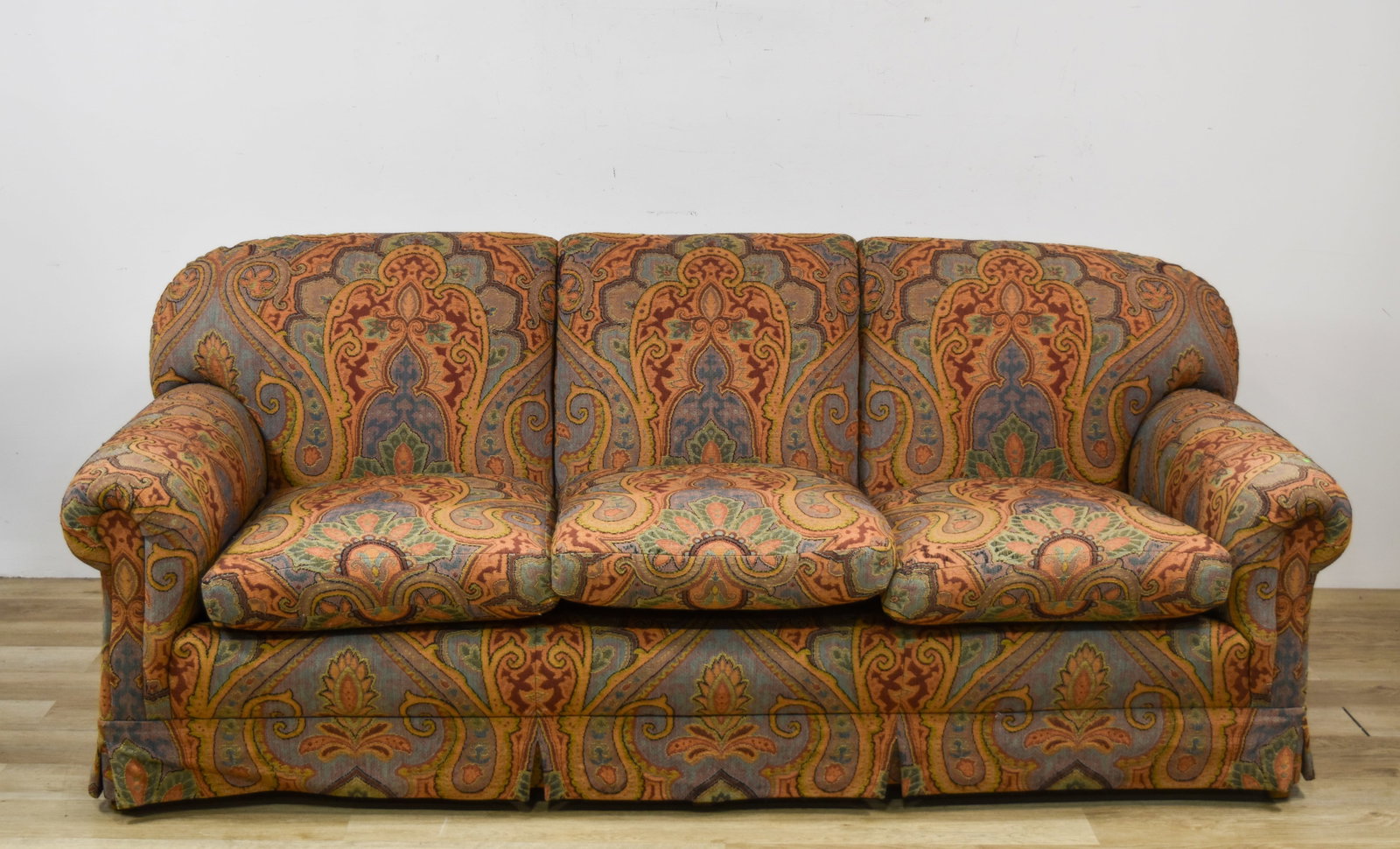 Three-Cushion Tapestry Upholstered Sofa with Paisley Pattern: This three-cushion sofa is constructed with a traditional silhouette featuring rolled arms and a kick-pleat skirt that covers the base. It is upholstered in a multi-color tapestry-weave fabric decorat