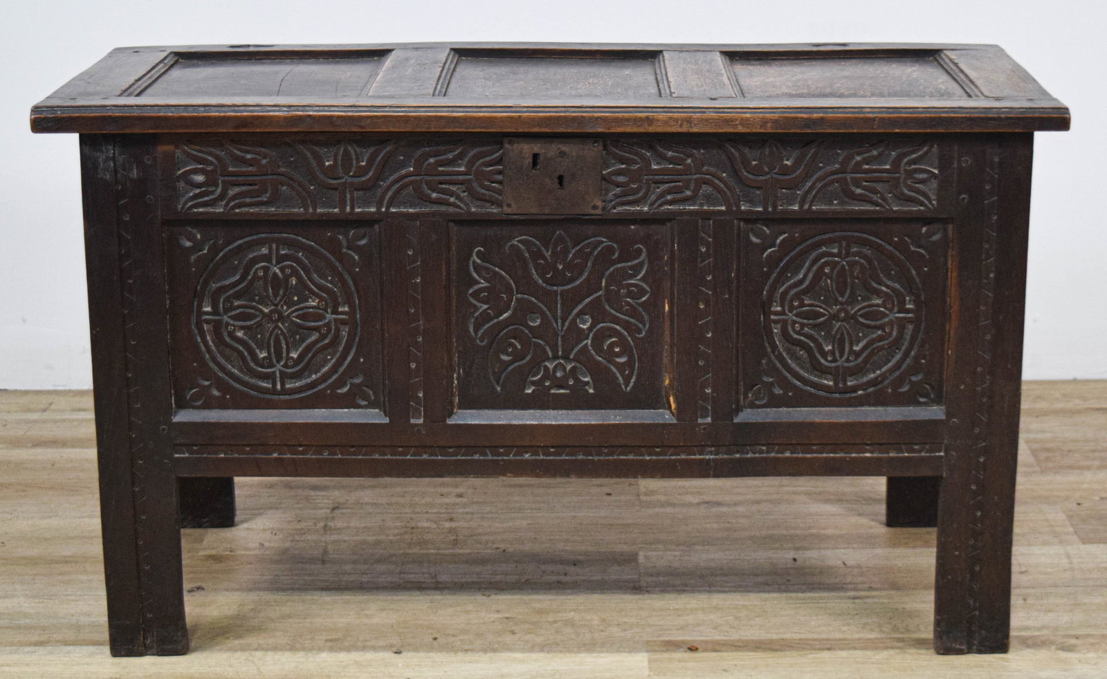 Jacobean Carved Oak Paneled Blanket Chest: Jacobean blanket chest or coffer, constructed from solid oak with a dark-stained finish. The chest features a three-panel front and a three-panel hinged top with cleated ends. The front panels are emb