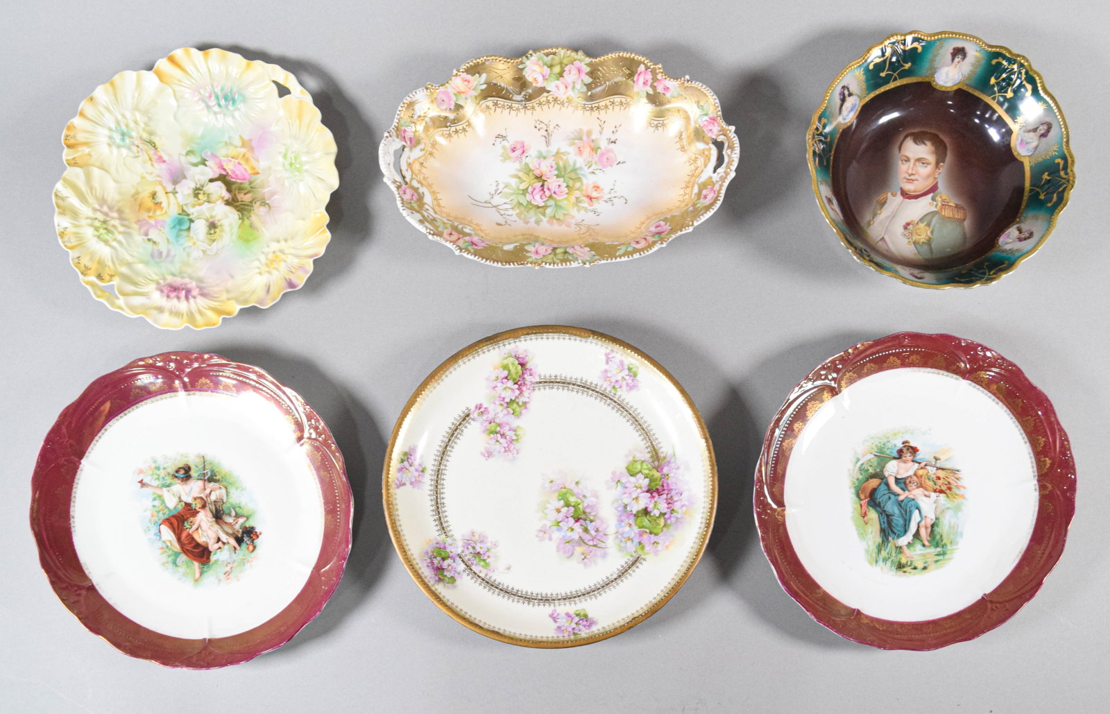 A Collection of Six Decorative Porcelain Plates and Bowls Including R.S. Prussia and Fraureuth: This lot consists of six pieces of decorative porcelain featuring floral, portrait, and pastoral motifs. The grouping includes pieces from European manufacturers including Reinhold Schlegelmilch and t