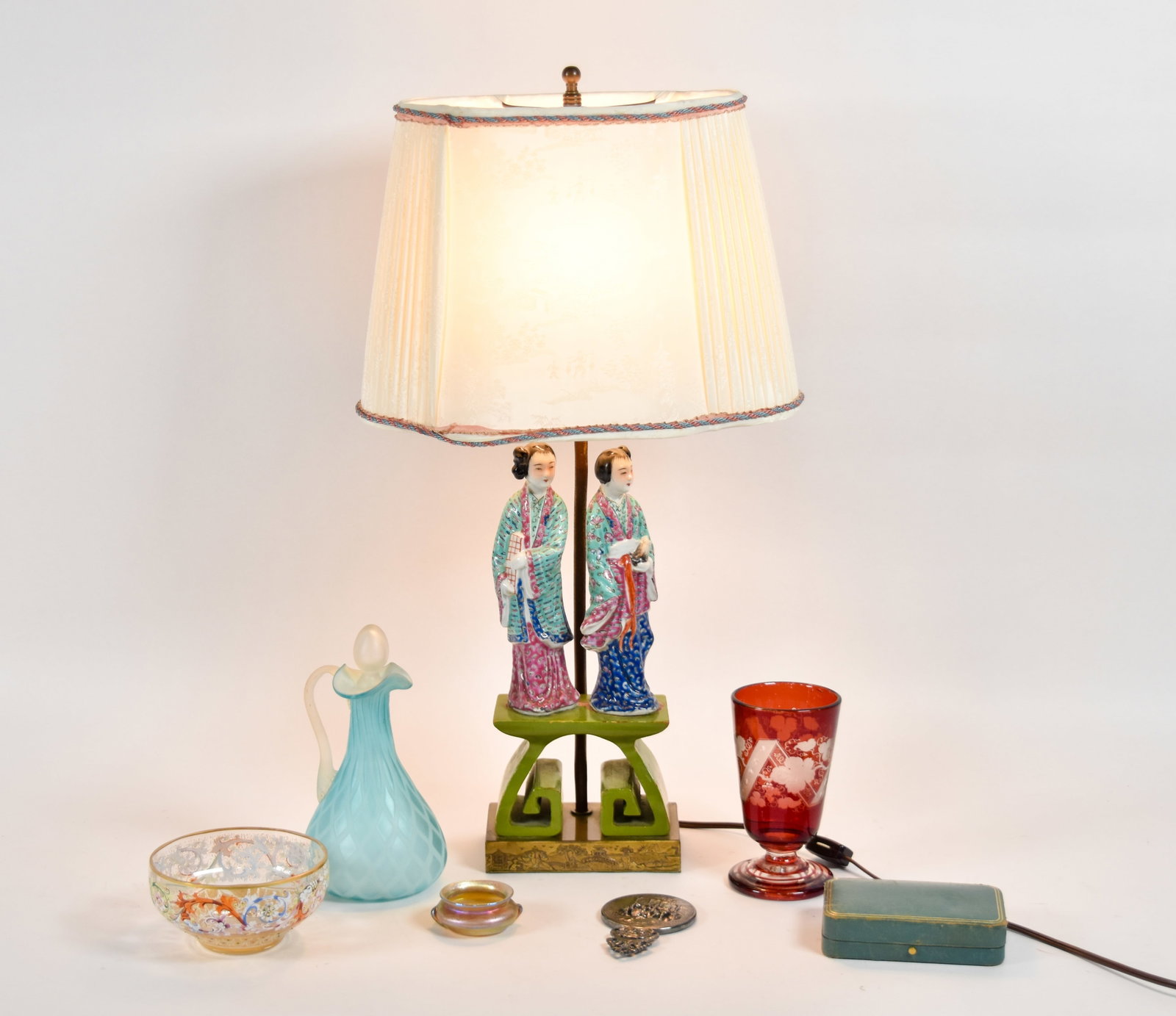 Assortment of Porcelain and Glass Decorative Table Items: Assortment of seven decorative table items including a Chinoiserie style porcelain and metal lamp, various art glass vessels, a silver-plated hand mirror, and a Tiffany and Co. presentation box. The l