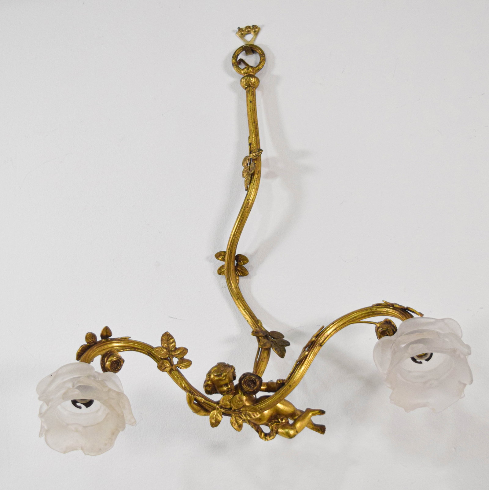 Rococo Revival Style Gilt Metal and Frosted Glass Wall Sconce: Rococo Revival style gilt metal and frosted glass two-light wall sconce. The central fluted stem is decorated with cast leaf motifs and terminates in a circular mounting loop. A cast metal winged cher