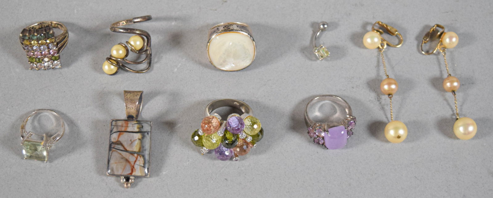 10 Pieces of Sterling Silver and Stone-Set Jewelry: An assortment of ten jewelry pieces featuring various semi-precious gemstones and silver settings. The collection includes six rings: a multi-row band pave-set with multi-colored stones; a sterling si