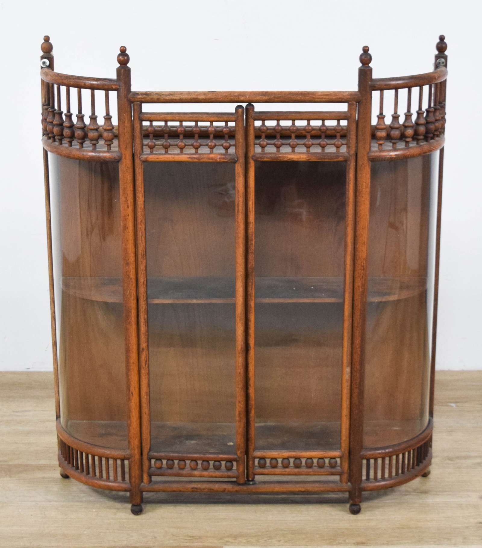 Aesthetic Movement Oak Wall Vitrine: Aesthetic Movement oak wall vitrine. The case is constructed with decorative spindle-turned galleries at the crown and base. Two hinged central doors with flat glass panels open to reveal an interior 