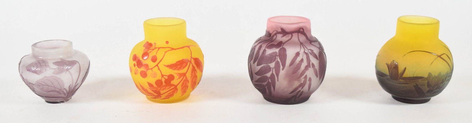 4 Gallé Style Cameo Glass Vases: Group of four Gallé style miniature cameo glass vases. Each vessel is constructed of acid-etched, multi-layered cased glass. The assortment includes a bulbous lilac and white frosted vase with a deep