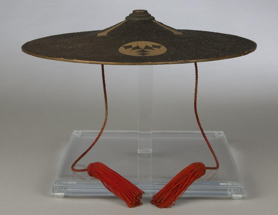 Edo Period Japanese Ichimonji-Style Jingasa: 16.5" diameter. Wood construction with textured black lacquer top and gold-leaf mixed red lacquer interior. Rim of gold lacquer. Top shows gilt mon (crest) with gilt cruciform motif. Red cords with ri