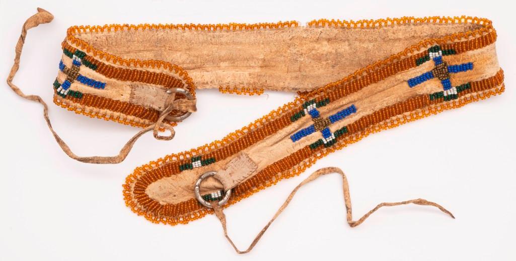 Beaded Hat Band: 23.5" x 2.75". Tanned hide construction with amber, gold, gree, blue, and white beads in a geometric motif trimmed in amber. metal loops with rawhide ties. **Good condition overall. Some staining and 