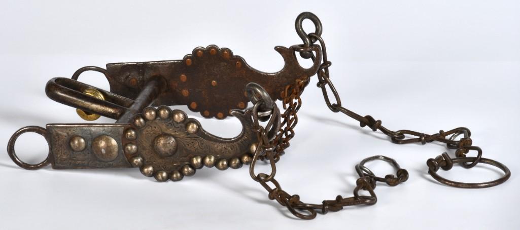 Silver-Mounted Bit: 7" x 5.25". Iron construction with brass roller. Features engraved silver inlaid in floral motifs as well as copper-shanked silvered studs. **Good condition overall. Overall dark smooth patination wit