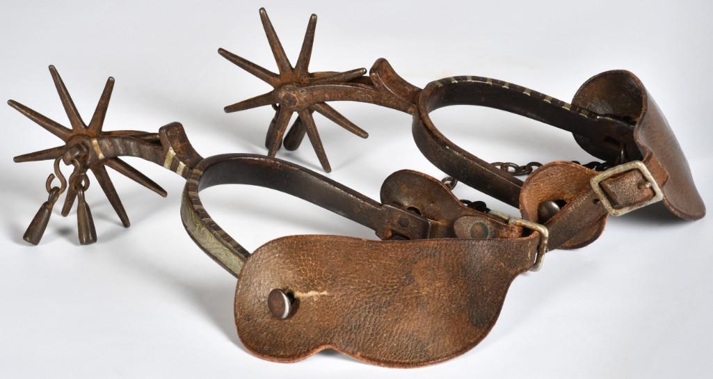 Pair of California-Style Spurs Attributed to Bill Picket: 8.75" x 4". Iron construction with engraved heel bands and inlaid shank. 3.75" eight-point rowel. Fitted with heel chains and jingle-bobs. Late 19th to early 20th century. **Good condition overall. Ov
