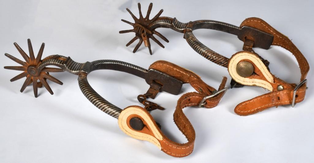 Pair of Silver Inlaid Spurs: 4" x 8.25". California-style with long neck, jingle-bobs, and 3" rowels. Heel bands inlaid with low-grade silver. Exterior strap buttons in the form of 1936-dated 5-centavos Aztec calendar coins. Incl