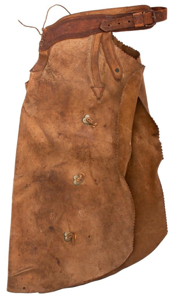 Pair of Leather Chaps Attributed to Bill Pickett: Leather construction with rounded edge trim and arrow reinforced pockets. Heart-shaped silver conchos with buckskin ties. Iron roller belt with rawhide front closure. Belt shows Miles City Saddlery st