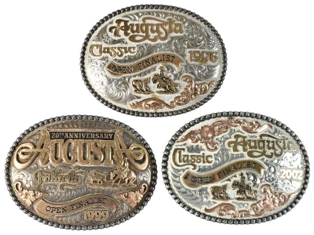 A Group of 3 Sterling and Gold Overlaid Belt Buckles: American, 20th century. A group of three belt buckles from the Augusta Classic finalist from years 1996,1999 and 2002, all buckles hand engraved by Gist silversmiths of California, each with Gist hall