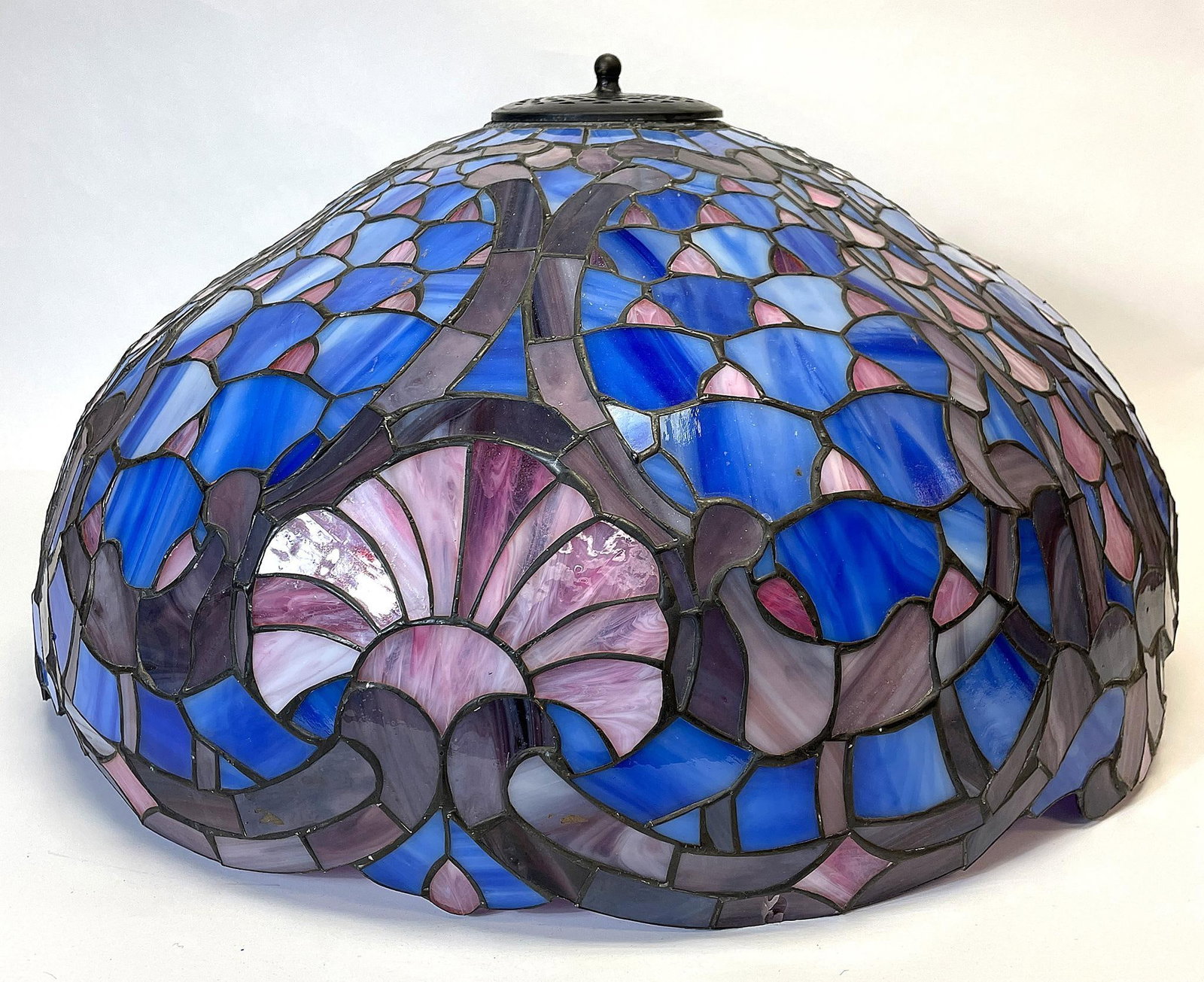 A Leaded and Stained Glass Lamp Shade: American, 20th century. A leaded and stained glass lamp shade with shell design; ht. 12, dia. 22 inches. Overall good condition. Very minor hairline cracks throughout. No visible repairs or maker mark