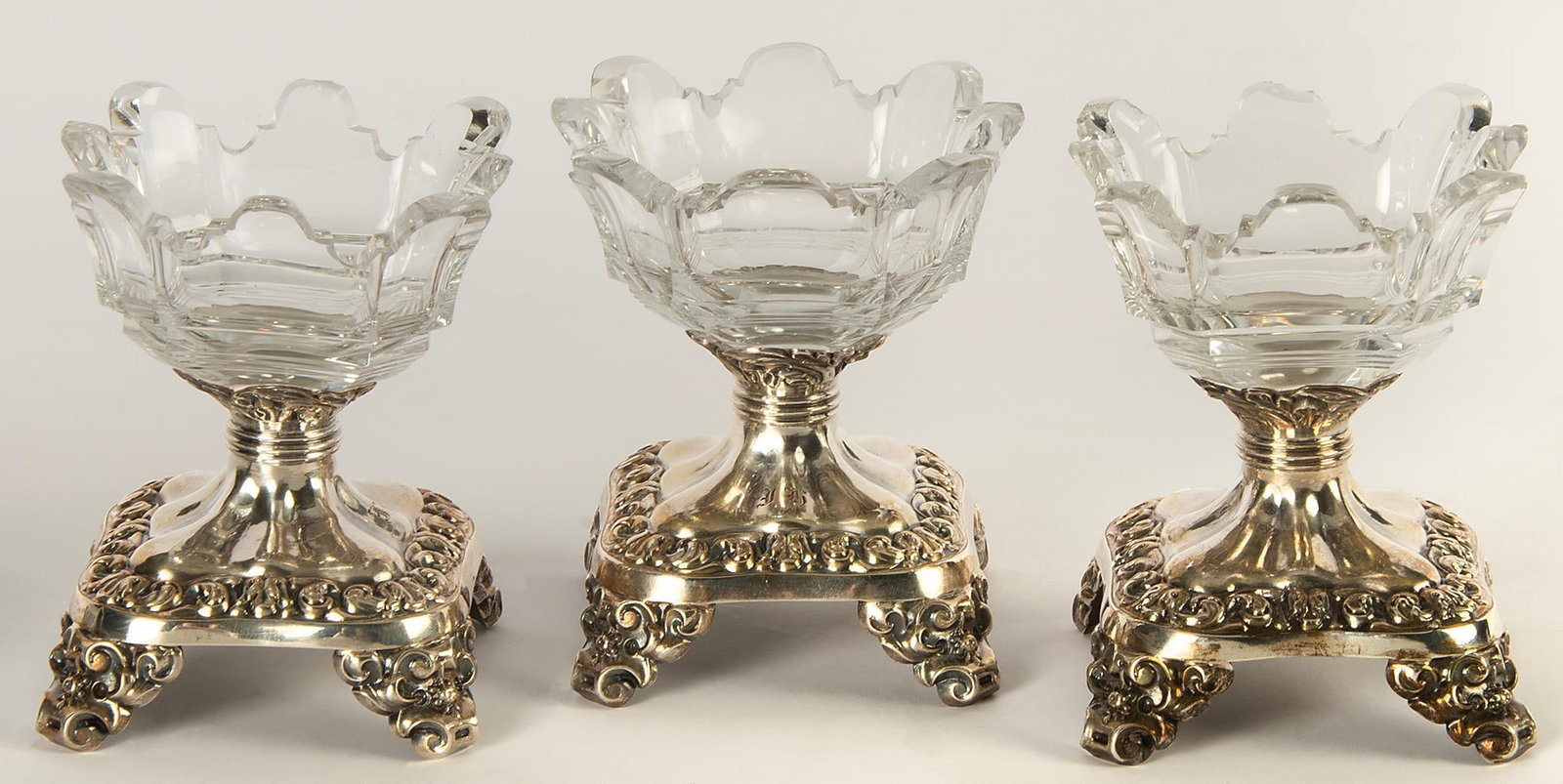 Three Crystal and Silver Salts: Continental, 20th century. A group of three footed salts in cut crystal with silver footed bases with monogram and no hallmarks; ht. 3.25, wd. 2.5, dp. 2.5 inches. Overall good condition.