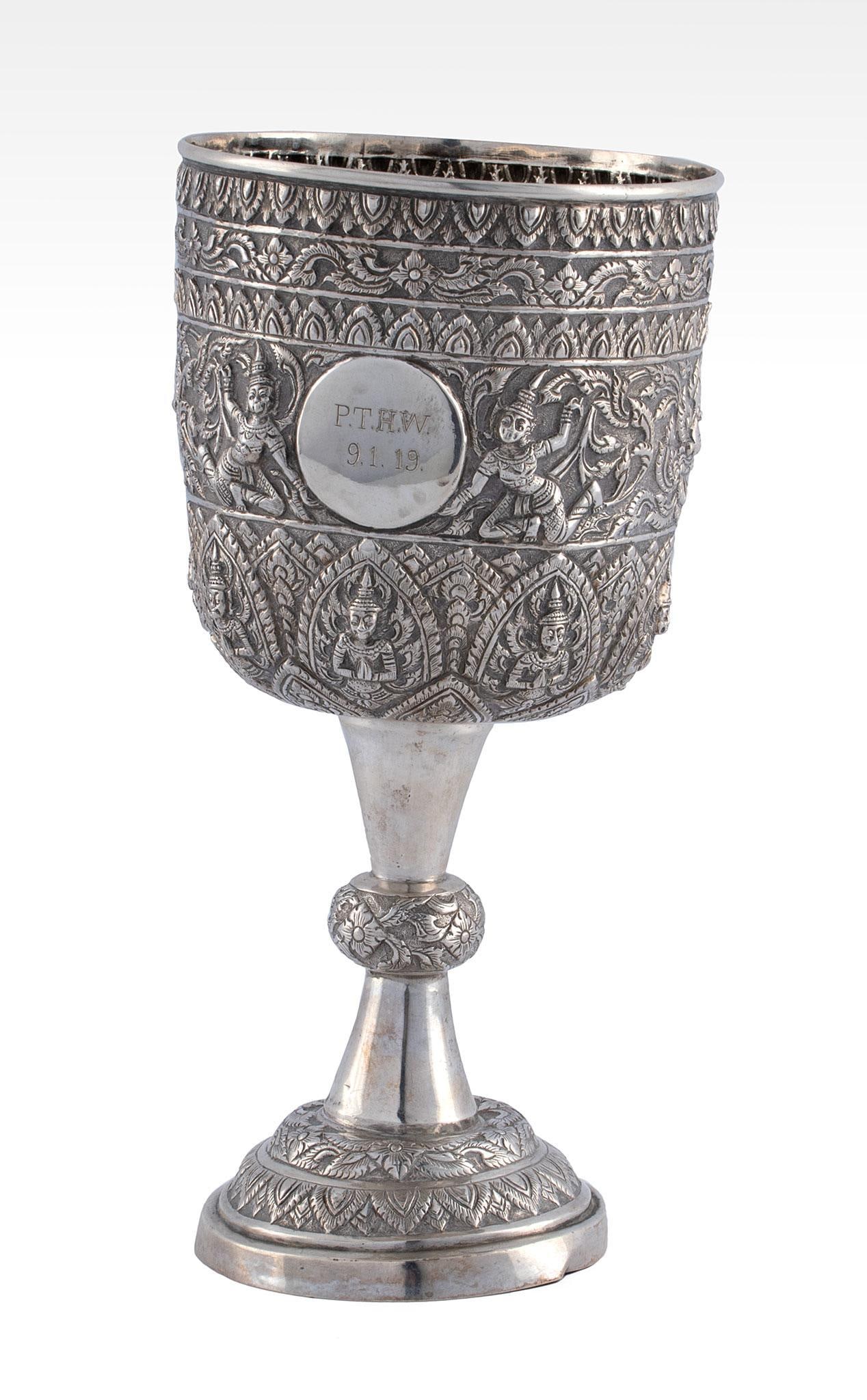 An Asian Saimese Repousse Silver Wine Goblet: Asian, 19th century. Siamese repousse decorated body with round step molded foot. ht. 8.5 x dia. 4 inches. 250 grams. Overall good condition. Central presentation date with initials to body. Provenanc