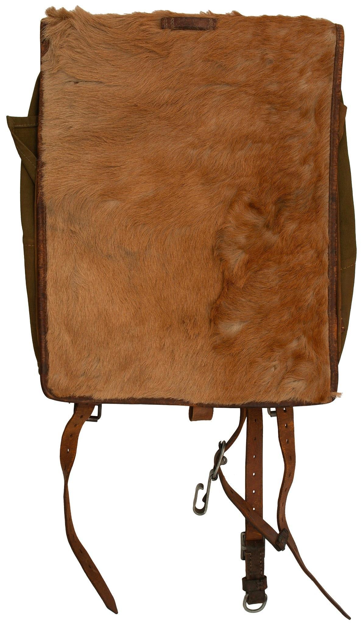 German Tornister: O.D. green canvas body with pony hair front flap. Three-strap interior. Rear shoulder strap supports marked with maker's stamp and 1939 date. Bottom leather reinforcement marked in ink " K. Forgriger 
