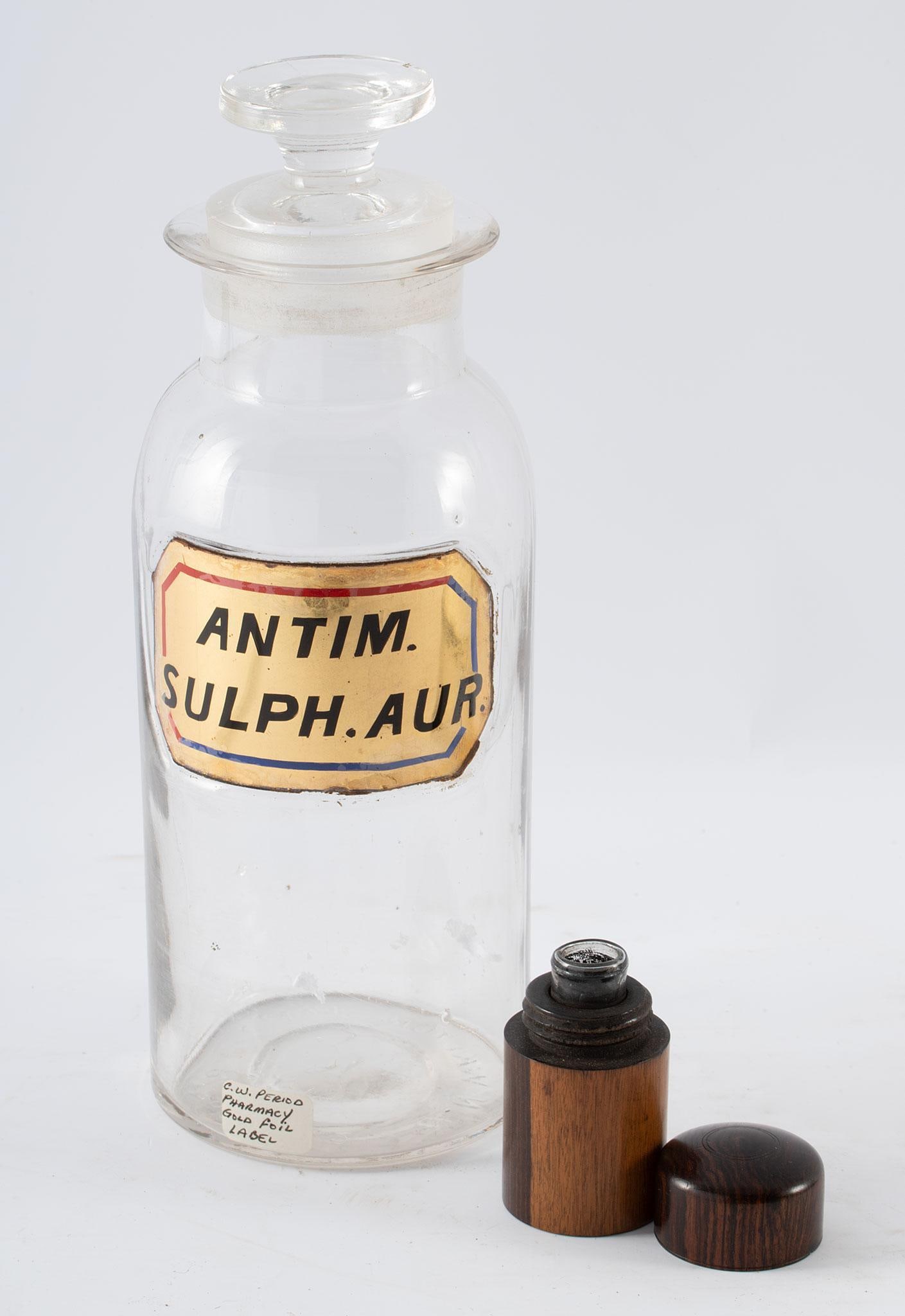A Group of 2 Vintage Pharmacy Bottles: One Apothecary bottle marked Antim. Sulph. Aur glass bottle with original label and one glass traveling medicine container housed in a wooded tube.