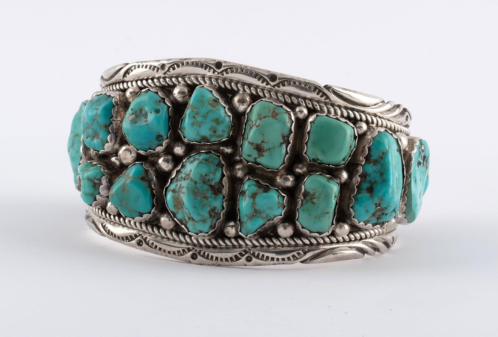 Navajo Sterling and Turquoise Bracelet: Native American, 20th century. A Southwest Navajo sterling silver and turquoise bracelet with "ST" hallmark stamp, decorative silver with 16 inlaid turquoise stones; ht. 2, wd. 3, dp. 2 inches. Overal