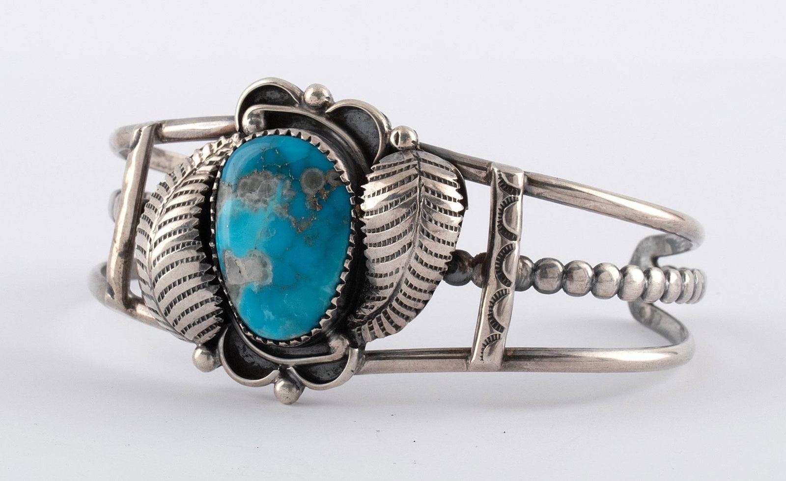 Navajo Sterling and Turquoise Bracelet: Native American, 20th century. A Southwest Navajo sterling silver and turquoise foliate and pierced bracelet with "RL" hallmark stamp, decorative silver with single inlaid turquoise stone; ht. 1.25, w