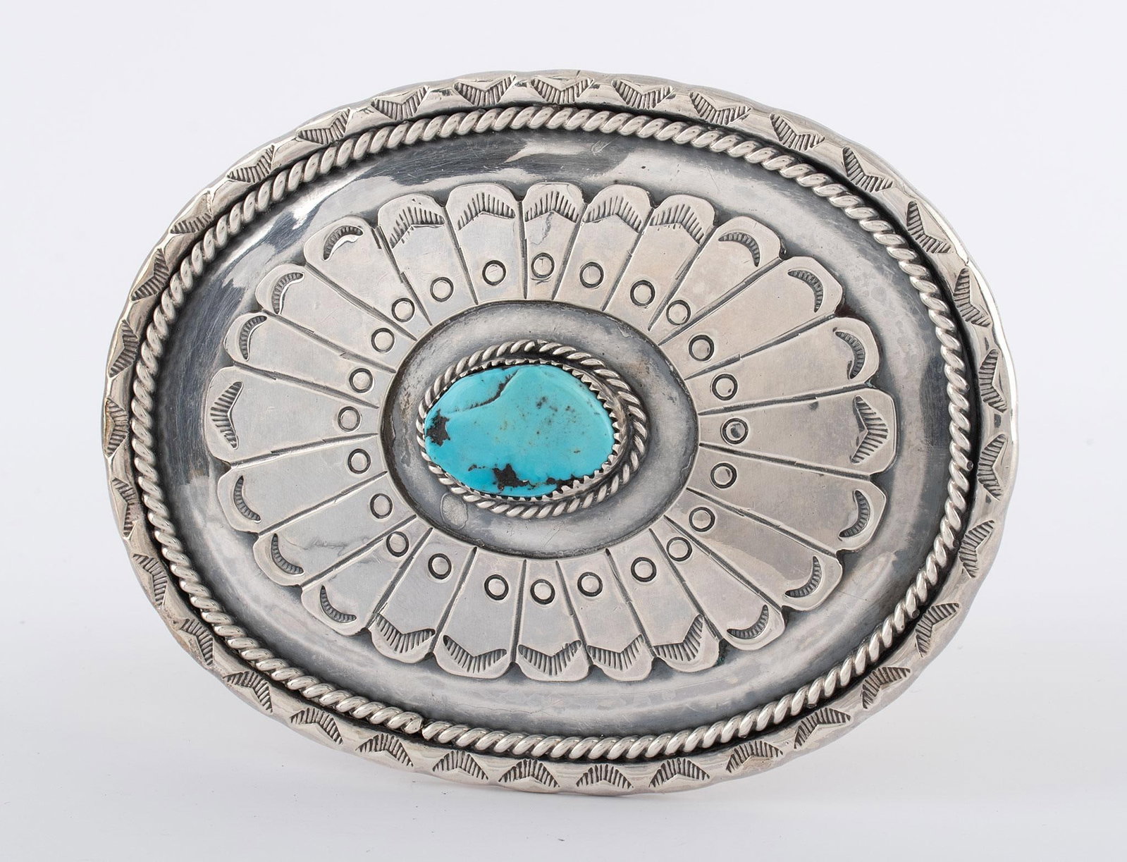 Navajo Silver and Turquoise Belt Buckle: Native American, 20th century. A Navajo silver and turquoise etched belt buckle with single central turquoise stone and feather design, scratch signature "TB"; 4 x 3 inches. Overall good condition.