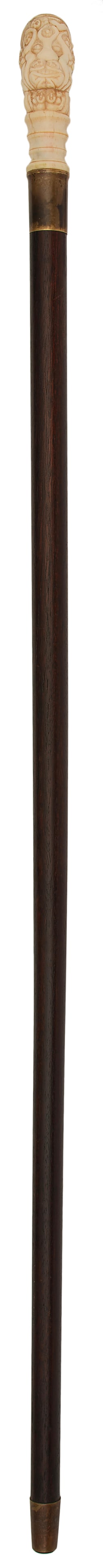 Asian Figural Carved Walking Stick: Asian, late 19th or 20th century. A wooden and brass cap walking stick or cane with erotic female nude figural bone carved handle depicting a face; 36 inch length. Overall good condition. Expected age